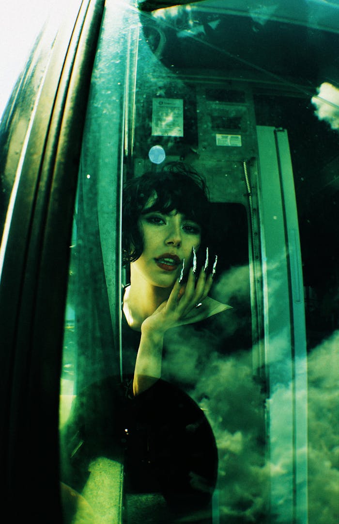 Stylish portrait of a woman seen through a reflective glass window with vivid colors.
